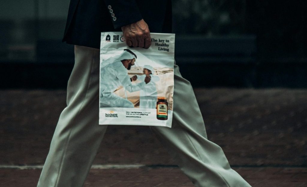 Side view of a businessman in Dubai holding a magazine while walking.